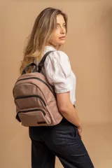 Mochila urbana de diseño funcional en color beige, confeccionada en tela impermeable. Cuenta con un compartimento principal amplio, un bolsillo secundario y un bolsillo frontal, todos con cierre. Incluye asa superior y correas ajustables para los hombros, con detalle de etiqueta de marca en el frente.