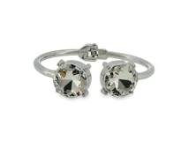 Brazalete rígido de metal plateado con dos grandes zirconias redondas en los extremos y cierre de bisagra.