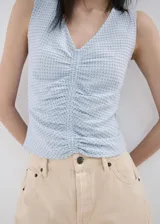Top celeste de tirantes con escote en V y diseño drapeado en el centro.