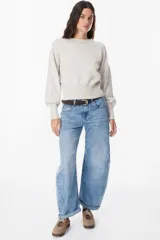 Sweater de punto color crudo con cuello redondo, mangas largas con puños anchos acanalados y cintura también acanalada. Presenta un diseño de silueta holgada y mangas con volumen.