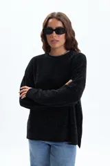 Sweater de tejido chenille en color negro, con cuello redondo, mangas largas y puños acanalados. Presenta una textura suave y un corte holgado.