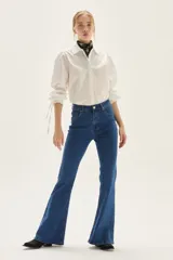 Jean acampanado de tiro alto, color azul medio, confeccionado en denim con un pequeño porcentaje de elastano.