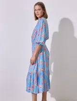 Vestido midi celeste con estampado floral en tonos naranja y rosa, de la marca Ruby Rd. Tiene cuello redondo con escote en V, mangas 3/4 con puños fruncidos y cintura elastizada en punto smock.