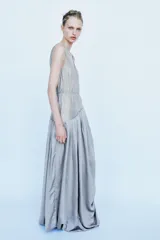 Vestido largo de tirantes con escote redondo, confeccionado en mezcla de viscosa. Presenta un diseño combinado con la parte superior en tejido ligero semitransparente y la parte inferior con volumen y drapeado asimétrico.