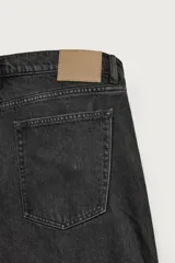 Jeans baggy fit de corte holgado en color negro con efecto lavado, confeccionados en denim de algodón rígido, con diseño clásico de cinco bolsillos y cierre frontal con cremallera y botón.
