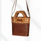 Bolso matero de cuero color marrón con estampado animal print en la parte superior y correa de cuero lisa desmontable.