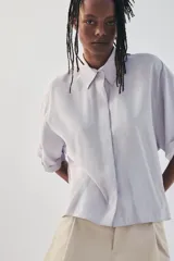 Camisa de manga corta color marrón oscuro, con cuello solapa, corte fluido y cierre frontal oculto con botones.