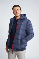 Campera puffer Mistral de hombre, color azul marino con cierre frontal y detalles en color rojo. Cuenta con capucha, puños elásticos y logo estampado en el pecho.
