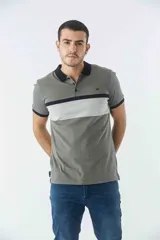 Remera tipo polo de manga corta con diseño de bloques de color en tonos verde oliva, gris y negro. Presenta cuello y puños a contratono, cierre frontal con botones y logo bordado en el pecho.