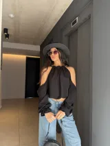 Blusa de manga larga y hombros descubiertos de color negro, con diseño halter fruncido en el cuello y mangas abullonadas caídas.