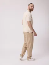 Remera tipo polo color beige, de manga corta y corte clásico, con cierre parcial frontal con cremallera.