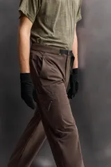 Pantalón de hombre color marrón oscuro, corte regular fit, confeccionado en tejido técnico compacto elástico. Presenta cintura ajustable con cinturón negro a contraste, bolsillos frontales, bolsillo trasero con cierre y bolsillo cargo con cierre en la pernera.