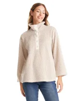 Buzo de tejido soft mohair con estampado zigzag en tonos beige y blanco. Presenta cuello polo, escote en V con botones a presión y manga larga amplia. El bajo tiene tajos laterales y apliques metálicos.