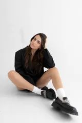 Mocasín de cuero color suela con punta cuadrada y suela track de goma oscura. Presenta un detalle de doble cadena metálica plateada sobre el empeine.