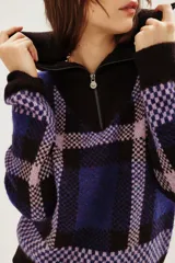 Cardigan de punto con diseño de cuadros en tonos azul, violeta y negro. Presenta cuello alto con cierre frontal y mangas largas.