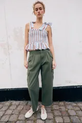 Pantalón cargo de tiro medio con pinzas delanteras, bolsillos laterales de plastrón y cierre frontal con cremallera y botón. Presenta una pernera holgada que se estrecha ligeramente hacia el bajo.