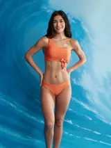 Conjunto de bikini color naranja, compuesto por un corpiño asimétrico de un solo hombro con lazo decorativo y una bombacha colaless.