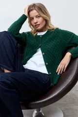 Cardigan de punto color verde oscuro con diseño de textura de rombos, cuello redondo y cierre frontal con botones a tono.