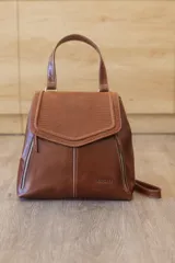 Mochila de cuero marrón Sagali, con solapa frontal en pico texturizada tipo reptil, bolsillos laterales con cierre y costuras pespuntadas en contraste. Incluye asa superior y correas ajustables.