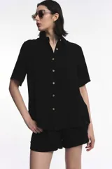 Camisa de manga corta color verde oliva, con cuello camisero, cierre frontal con botones y diseño fluido y relajado.