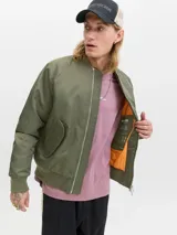 Campera tipo bomber color verde oliva, con cierre frontal de doble dirección, cuello, puños y ruedo acanalados. Presenta bolsillos laterales con solapa y forrería interna.