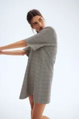 Vestido corto con estampado a cuadros en blanco y negro, escote en V y mangas cortas.