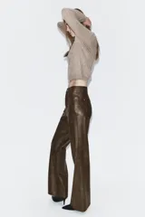 Pantalón de tiro medio confeccionado en tejido efecto piel, con diseño de cinco bolsillos y cierre frontal con cremallera y botón.