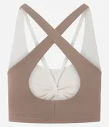 Top deportivo de microfibra marca Get Over, de diseño bicolor en tonos marrón y marfil, con escote redondo, capas superpuestas, breteles anchos cruzados y abertura en la espalda.