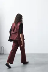 Chaleco de estilo utilitario color bordó con pespuntes blancos a contratono. Presenta solapas, cierre frontal con botones, bolsillos delanteros y un diseño estructurado.