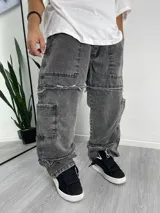 Pantalón baggy gris con efecto lavado, bolsillos laterales y detalles rotos en las rodillas.