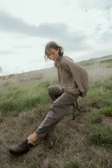 Camisa de manga larga con estampado cuadrillé en tonos marrones y negros, cuello alto con volados y puños elásticos.