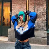 Campera de punto negra con franja azul y letras blancas con la palabra 'EME' en el pecho. Tiene cuello polo, cierre frontal con cremallera y corte oversize.