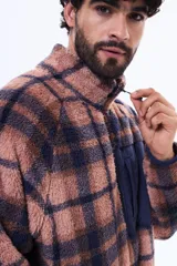 Campera de sherpa con diseño a cuadros en tonos marrón y azul marino. Presenta cuello alto, cierre frontal parcial y un bolsillo frontal con cierre en contraste de color azul marino.