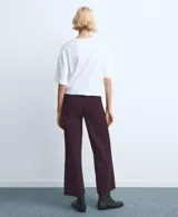 Jeans color bordó, de corte wide leg y tiro medio, con bolsillos laterales y traseros, y terminación sin dobladillo en los tobillos.