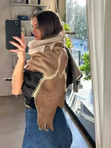 Ruana artesanal confeccionada con piezas de napalán unidas mediante costuras de crochet. Presenta un diseño de patchwork en tonos tierra, marrones y crema, con capucha integrada.