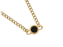 Collar de acero con baño de oro y dije circular con ónix negro.