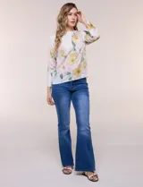 Blusa de silueta holgada y corte recto con caída fluida, escote redondo y mangas largas con puños anchos estructurados, con estampado floral en tonos pasteles sobre fondo blanco.
