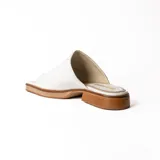 Zueco artesanal de cuero color dorado, con suela plana y taco bajo de madera con plataforma.