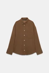 Camisa de corte oversize con cuello solapa, manga larga con hombro caído y puños. Presenta un bolsillo de plastrón en el frente, pinza en la espalda y cierre frontal con botones.