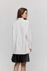Camisa de algodón blanca de calce relajado, con cuello clásico, mangas largas y cierre frontal con botones.