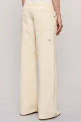 Pantalon de mezclilla color marfil con diseño cruzado asimétrico en la cintura, perneras anchas de corte relajado y detalles de roturas sutiles en la rodilla y el bolsillo.