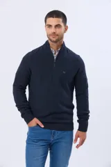 Buzo de punto texturado color azul marino, con cuello alto y cierre frontal parcial. Presenta puños y ruedo acanalados, con un pequeño logo bordado en el pecho.