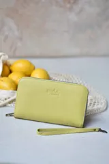 Billetera mediana color verde pistacho con cierre perimetral y correa de muñeca extraíble.