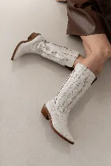Bota de estilo texano confeccionada en cuero genuino, con caña alta y diseño de costuras decorativas en contraste. Presenta punta fina y taco cuadrado de madera.