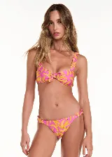 Conjunto de bikini marca Triya con estampado de bananas rosas y amarillas. El corpiño es de tirantes con volados y tiene un lazo extraíble. La bombacha tiene volados laterales.