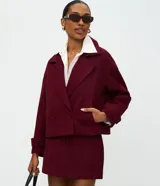 Abrigo corto tipo blazer de color bordó con estampa de espiga, cuello con solapas, cierre cruzado con dos botones y bolsillos ribeteados.