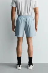 Pantalones deportivos cortos de tejido técnico ligero y elástico, con cintura elástica ajustable, bolsillos frontales y aberturas laterales en el bajo.