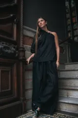 Pantalón negro de corte amplio con pinzas en la cintura, ajustable con elástico y tiras.