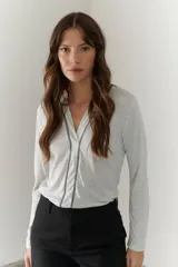 Remera manga larga color gris claro con escote en V y detalle de costuras en contraste.