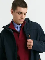 Campera softshell color verde militar, con capucha ajustable, cierre frontal completo y bolsillo vertical en el pecho con detalles en naranja.